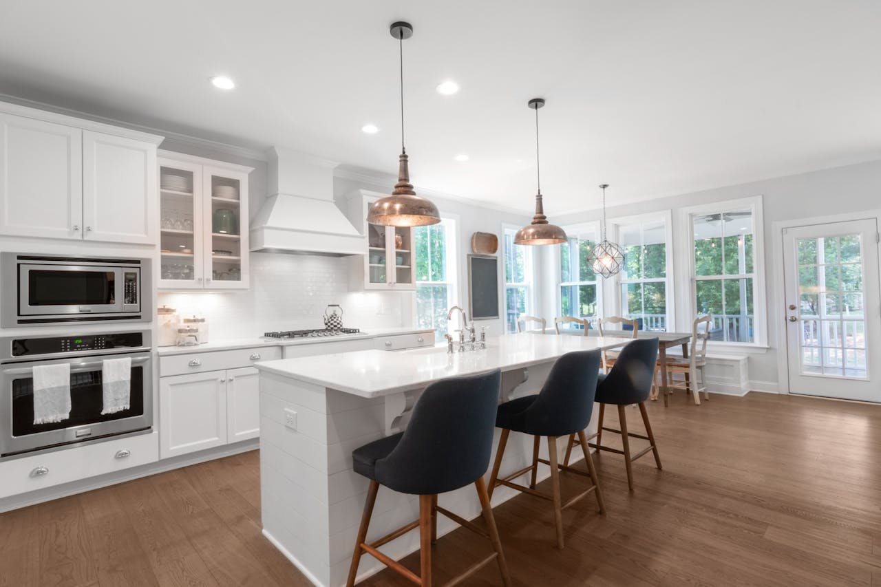 about-me Bright and elegant modern kitchen with white cabinets, dining area, and island bar.